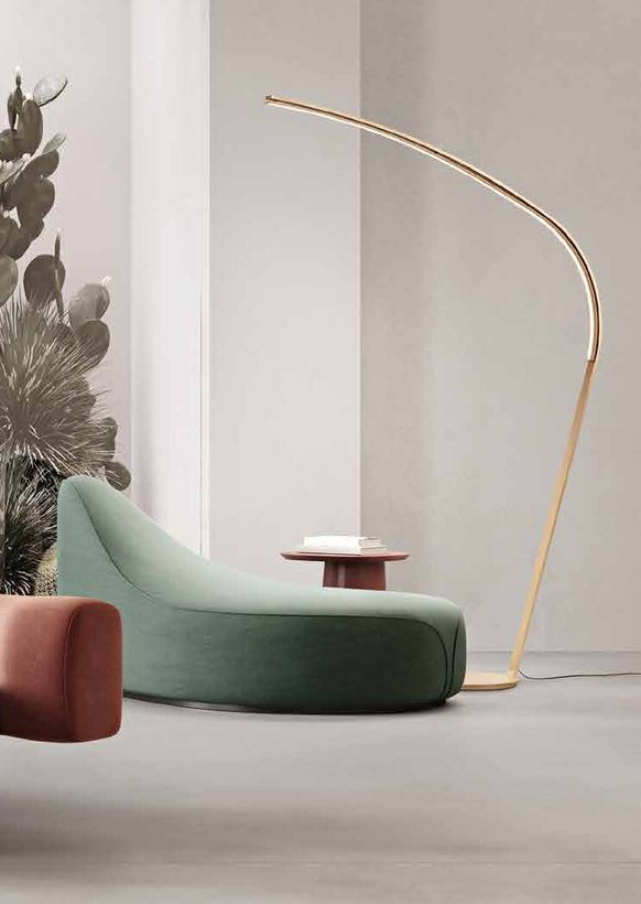 Finch gold arc floor lamp over a green chaise