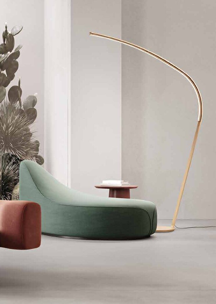 Finch gold arc floor lamp over a green chaise