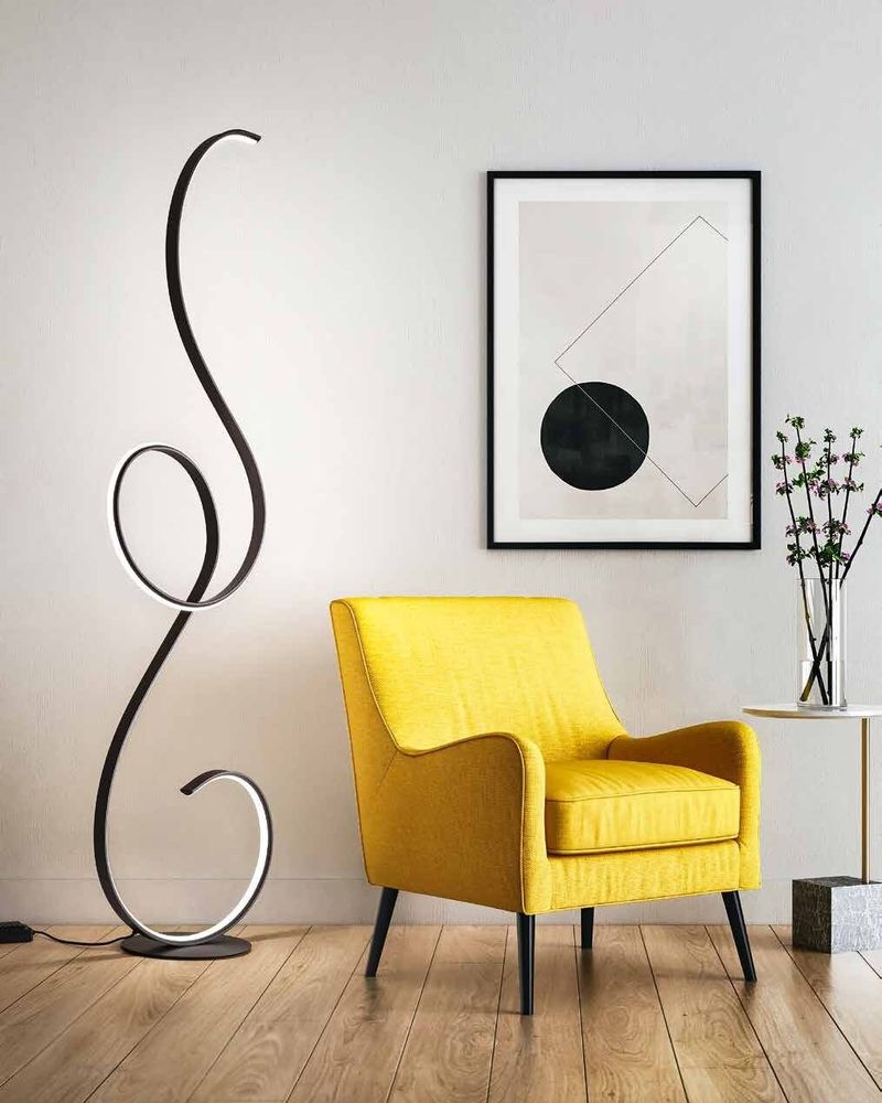 Wren black ribbon floor lamp beside a yellow armchair